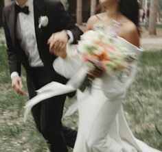 a bride and groom are running through the grass with their wedding bouquet in hand,