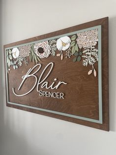 a wooden sign with flowers on it that says, hair spencer in white letters and brown background