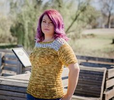 a woman with pink hair standing on a wooden bench