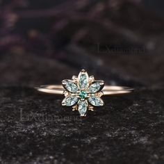 a gold ring with green and white stones on top of a black stone surface in front of a dark background