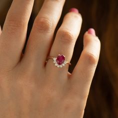 a woman's hand with a diamond and ruby ring on her finger, close up