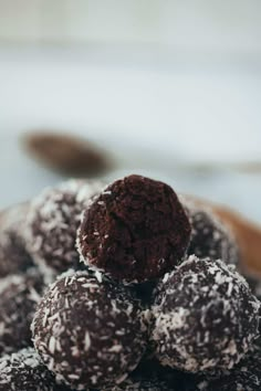 chocolate truffles piled on top of each other in a bowl with powdered sugar