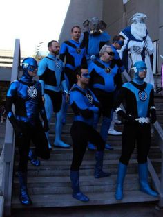 a group of men in blue and black costumes standing on steps with one man dressed as catwoman