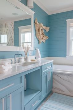 a bathroom with blue walls and white counter tops, along with a large bathtub