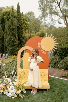 a pregnant woman standing in front of an orange and yellow couch with flowers on it