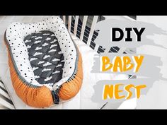 an orange and white baby nest sitting on top of a bed with the words diy