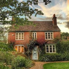 an old brick house with ivy growing on it's roof and windows in the front