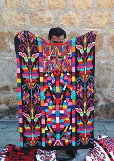 a man is holding up a colorful quilt