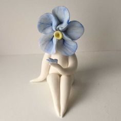 a ceramic figurine with a blue flower on it's head