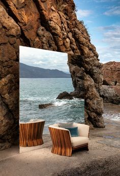 two chairs sitting next to each other in front of a large mirror on the beach