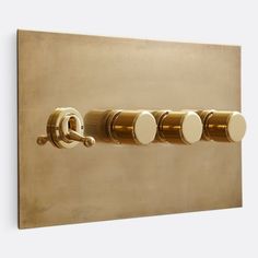 three round knobs on the side of a gold wall mounted light switch with four white knobs