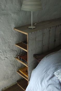 a bed with a lamp on top of it next to a book shelf and pillow