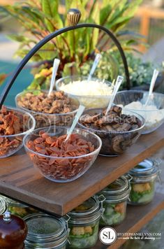 several bowls of food are on a table with jars and spoons next to them