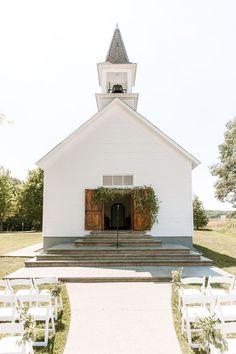 an outdoor wedding ceremony with white chairs and greenery on the steps leading up to the church