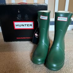 green hunter boots sitting on the floor next to a box