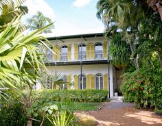 a large white house surrounded by trees and plants