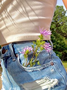 a person with their back to the camera holding a flower in his jeans pocket,