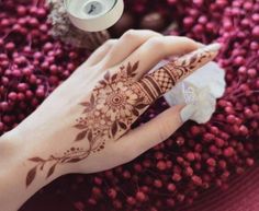 a henna on someone's hand next to some flowers