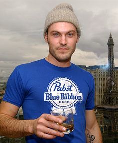 black and white photograph of a man holding a drink in front of the eiffel tower