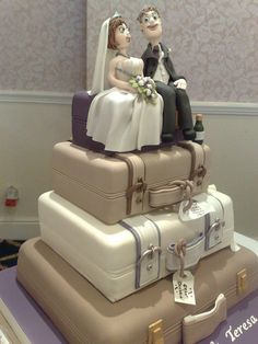 a wedding cake made to look like suitcases with a bride and groom on top