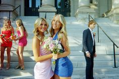 two beautiful young women standing next to each other in front of some stairs with flowers