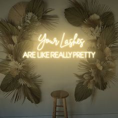 a neon sign that says your lashes are like really pretty on the wall next to a stool