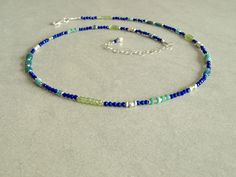 This multi gemstone blue lapis necklace has an array of gorgeous small gemstones -- small blue lapis lazuli, rare Ethiopian teal opals, green peridot, teal apatite, and Sleeping Beauty turquoise, with a variety of sterling silver beads. This slender blue lapis multi gemstone necklace closes with a sterling silver lobster clasp, and has a small lapis charm at the closure. The small natural gemstones in this necklace are so beautiful together, and come in many shapes and sizes. The blue lapis is r Dainty Blue Necklace With Natural Stones, Blue Sterling Silver Necklaces With Tiny Beads, Sterling Silver Blue Jewelry With Tiny Beads, Blue Sterling Silver Jewelry With Tiny Beads, Blue Sterling Silver Beaded Necklace With Faceted Beads, Blue-green Round Beads Jewelry For Gifts, Blue-green Round Beads Jewelry Gift, Dainty Blue Gemstone Bead Jewelry, Dainty Blue Jewelry With Natural Stones