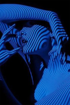 a woman's head is shown with blue light on her face and hands, in the dark