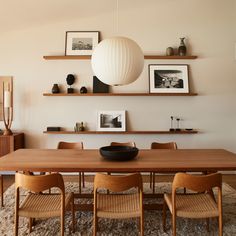 a dining room table with chairs and pictures on the wall above it, along with other furniture