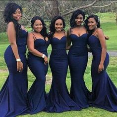 four beautiful women in blue dresses posing for the camera with trees in the back ground