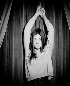 black and white photograph of a woman holding an umbrella in front of curtained area