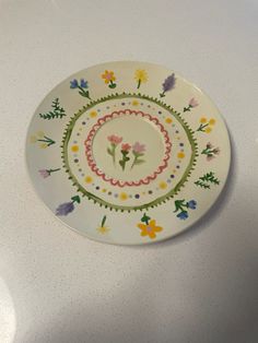 a plate with flowers painted on it sitting on a white counter top next to a knife and fork