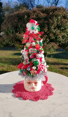 a small christmas tree is sitting on top of a table in front of some trees