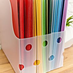 several folders are stacked together on a wooden table with a plant in the background