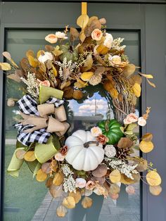 a wreath with fall leaves and pumpkins hanging on the front door for autumn decor