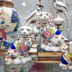 some very pretty ceramic animals on display in a glass case with flowers and birds around them