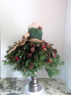 a christmas arrangement with pine cones, berries and a teddy bear sitting on top of it