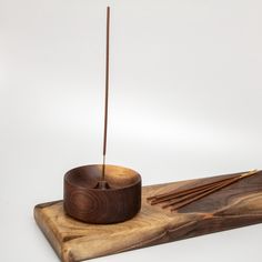 a wooden bowl with two sticks sticking out of it on a cutting board next to some chopsticks