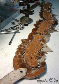 some tools are laying on a table with cow hides and other things to sew