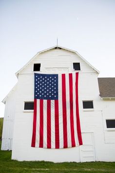 an american flag hanging on the side of a white barn