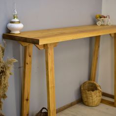 a wooden table sitting on top of a hard wood floor next to a basket and vase