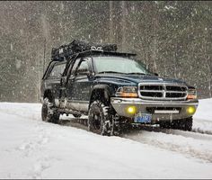 a black truck driving down a snow covered road