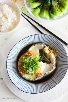 a plate with some food on it and chopsticks next to the bowl full of rice