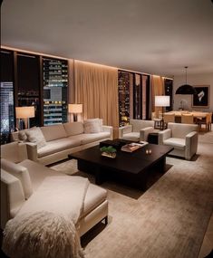 a living room filled with white furniture and tall buildings in the background at night time