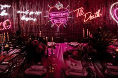 a table set for dinner with neon lights and decorations on the wall behind it,