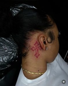 a woman with a tattoo on her neck and behind her ear is sitting in a chair