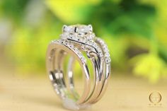 two wedding rings with diamonds on them sitting in front of green leaves and flowers,