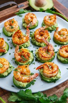 shrimp and avocado stuffed cucumbers on a white plate with cilantro