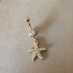 Gold Starfish Belly Button Ring - gold belly ring, crystal belly ring, beach lover gift Pretty belly ring in surgical steel colored GOLD with a double gem in clear and a rhinestone encrusted starfish with embossed detal (shown in hand in silver)   entire piece approx 1 5/8" long. /42mm 14 gauge Large barbell rhinestone approx 7mm across - star pendant Approx 7/8 (24mm) long  Comes in an organza gift bag matching necklace available To keep the rhinestones looking their best I recommend you do not wear this piece while swimming or bathing. NOT RECOMMENDED FOR THOSE WITH SENSITIVE SKIN, METAL ALLERGIES, OR NEW PIERCINGS also in silver https://www.etsy.com/listing/194426643/belly-button-ringstarfish-bellybutton?ref=shop_home_active_3 I DO NOT OFFER RETURNS or EXCHANGES, so please select carefu Starfish Belly Button Piercing, Cute Gold Belly Button Piercing, Gold Navel Jewelry, Gold Belly Button Jewelry, Belly Button Jewellery, Beachy Belly Button Piercing, Star Belly Button Piercing, Summer Belly Button Rings, Belly Button Piercing Gold