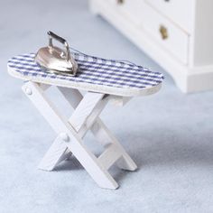 a miniature ironing board with a blue and white checkered table cloth on it